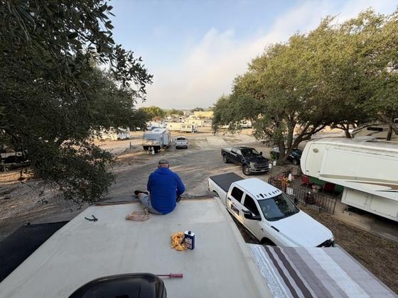 A technician cleaning an RV roof by hand before coating